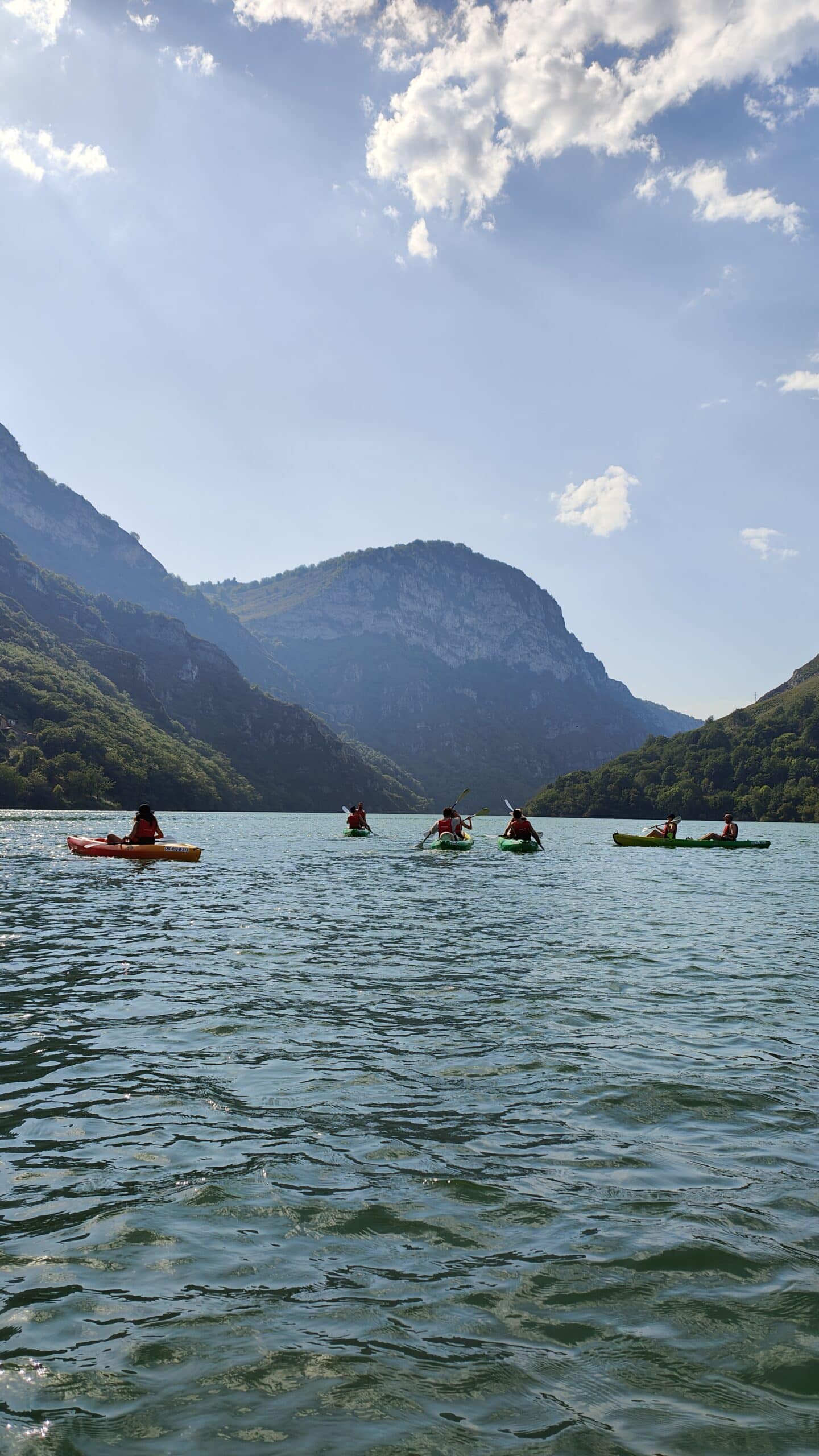 Gente en kayak en lago montañoso con sol brillante.